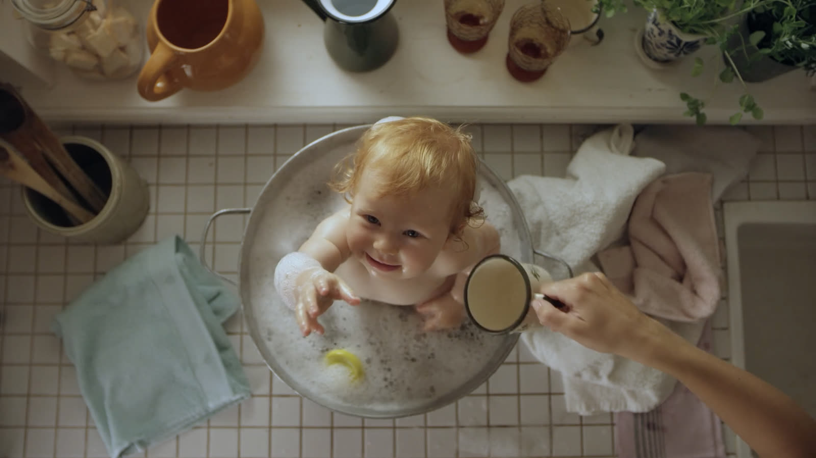 Overhead POV bathing a baby in a sink